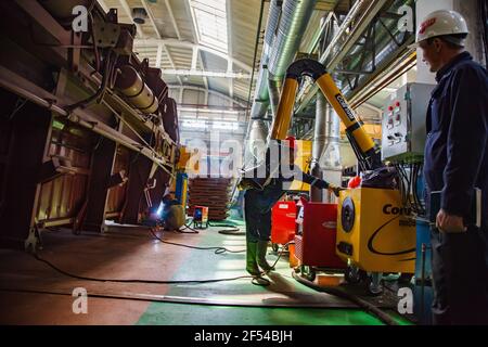 Ekibastuz, Pavlodar reg., Kasachstan: Eisenbahnkraftwagenbau. Drei Schweißer in der Werkstatt. Gelbe flexible Rohre des Abzugs. Stockfoto