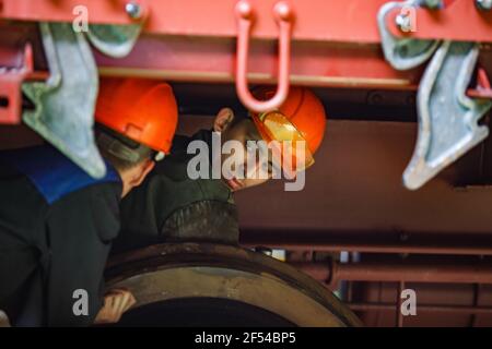 Ekibastuz, Region Pavlodar, Kasachstan Mai 28 2012: Autofabrik. Zwei junge Arbeiter unter dem Auto. Stockfoto