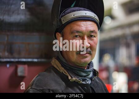 Ekibastuz, Region Pavlodar, Kasachstan - 28. Mai 2012: Wagenbauwerk. Porträt eines asiatischen Schweißerarbeiters mit Schutzmaske. Stockfoto