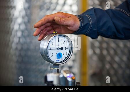 Ekibastuz, Kasachstan - 28. Mai 2012. Produktionsanlage für explosive Materialien für den Steinbruch. Manometermessgerät und Arbeitshand. Nahaufnahme. Stockfoto