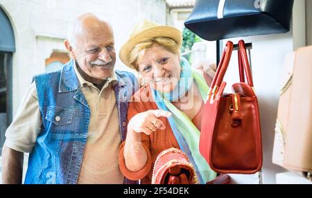 Ältere Paar einkaufen im Mode Tasche Geschäft mit Frau zeigt Showcase to Husband - Active Elderly Konzept mit reifen Mann Und Frau, die Spaß hat Stockfoto