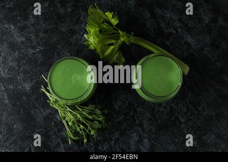 Gläser mit grünem Smoothie und Zutaten auf schwarzem Smokey Tisch Stockfoto