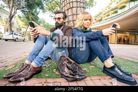 Hipster Millennial Paar in Desinteresse Moment mit Smartphone - Apathie Konzept über Traurigkeit und Isolation mittels Handy Stockfoto