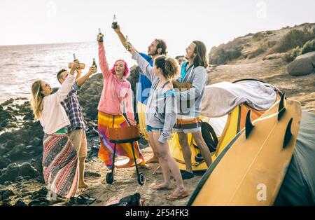 Hipster-Freunde haben gemeinsam Spaß auf Strand-Camping-Party - Freundschaftsreisekonzept mit jungen Leuten Reisende toasten und trinken Bier in Flaschen Stockfoto