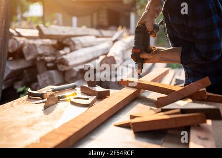 Hand von Carpenter bohrt Holz ein Loch mit einem elektrischen Bohrer. Stockfoto