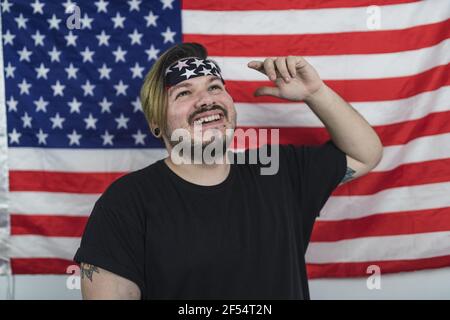 Bärtiger kaukasischer Mann lächelt, während er vor dem posiert US-Flagge Stockfoto