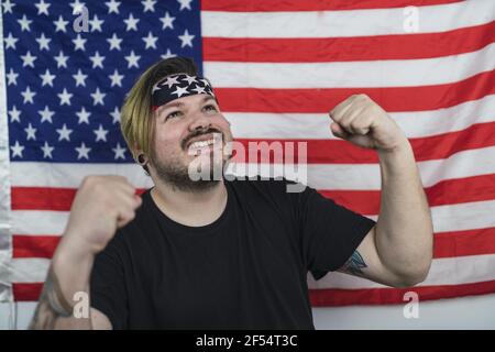 Bärtiger kaukasischer Mann lächelt, während er vor dem posiert US-Flagge Stockfoto