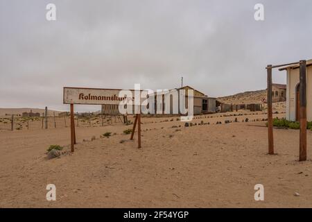 Das Schild Kolmannskuppe bei der Geisterstadt Kolmannskuppe In Namibia mit den verlassenen Gebäuden in der Namib Wüste Stockfoto