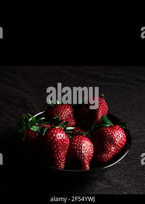 Frische Erdbeeren in einer Schüssel. Dunkles Essen. Stockfoto