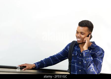 Porträt eines lächelnden jungen Mannes, der auf der Rolltreppe steht und darüber spricht Mobiltelefon Stockfoto