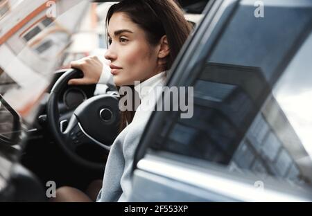 Nahaufnahme einer eleganten Geschäftsfrau, die im Auto zur Arbeit fährt. Erfolgreiche Unternehmerin fahren zum Treffen, öffnen Fahrertür Stockfoto