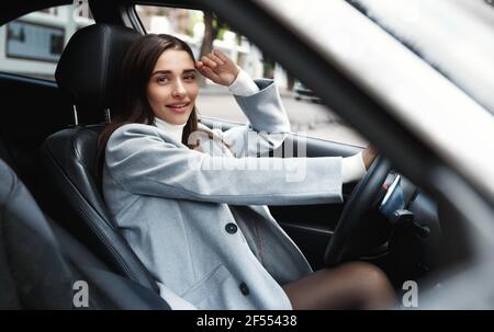 Elegante Geschäftsfrau Auto fahren, lächelnd glücklich. Attraktive weibliche Führungskraft, die in ihrem Fahrzeug arbeiten will Stockfoto