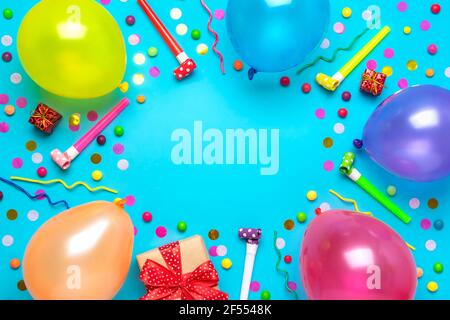 Bunte Party-Rahmen mit roten Geschenk-Box mit verschiedenen Partei Konfetti, Luftballons, Luftschlangen, Pokers und Dekorationen auf blauem Hintergrund. Urlaubskarte flach Stockfoto