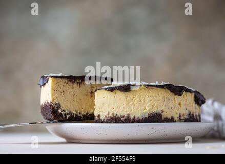 Köstliche cremige Käsekuchen mit Schokolade Glasur und Mandel, hellen Beton Hintergrund dekoriert. Kein Nachtisch mit Mousse. Selektiver Fokus. Stockfoto