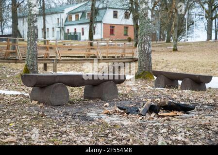 Holzbank aus Baumstämmen und ein Kamin in der Natur. Rastplatz im Park. Frühlingslandschaft Stockfoto