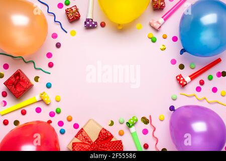 Bunte Party-Rahmen mit roten Geschenk-Box mit verschiedenen Partei Konfetti, Luftballons, Luftschlangen, Pokers und Dekorationen auf rosa Hintergrund. Urlaubskarte flach Stockfoto