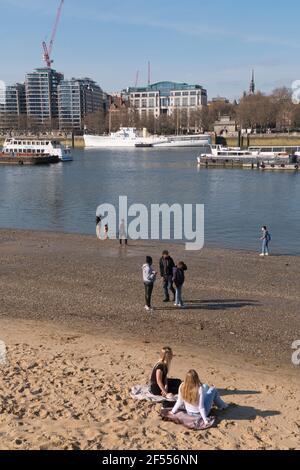 Freunde genießen einen sonnigen Frühlingstag am Strand von Bankside an der Themse in London. Stockfoto