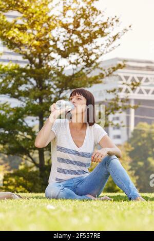 Ganzkörperportrait einer Frau, die barfuß im Wasser sitzt Gras Stockfoto