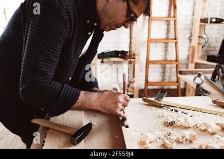 Zimmermann macht Bleistiftspuren auf einem Holzbrett Stockfoto