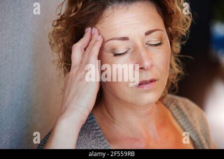 Nahaufnahme Porträt einer älteren Frau mit Hand an Kopf In Schmerzen Stockfoto