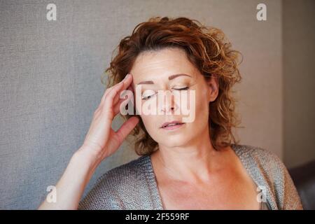 Nahaufnahme Porträt von Frau mittleren Alters mit der Hand zu Kopf in Schmerzen Stockfoto