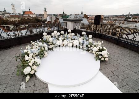 Ein wunderbarer Ort in den Dekorationen und Blumen für die Hochzeitszeremonie mit weißen Stühlen auf dem Dach des Hotels. Hochzeitszeremonie Stockfoto