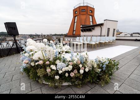 Ein wunderbarer Ort in den Dekorationen und Blumen für die Hochzeitszeremonie mit weißen Stühlen auf dem Dach des Hotels. Hochzeitszeremonie Stockfoto