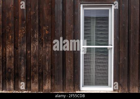 Alte Holzfassade eines Wohngebäudes mit einem neuen Fliegenschirmtür in die Terrassentür eingebaut Stockfoto