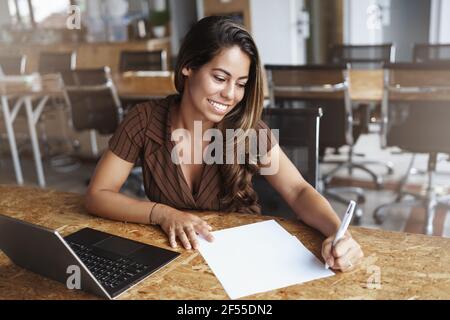 Attraktive stilvolle erfolgreiche Geschäftsfrau Unterschrift Papiere Überprüfung Dokumente lesen lächelnd Begeistert sitzen Co-Working-Raum allein freiberuflich arbeiten Stockfoto