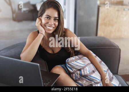 Attraktive stilvolle fröhliche moderne Geschäftsfrau liegen komfortable Bürocouch reden Mitarbeiter lächelnd erfreut aussehen Kamera arbeiten Laptop Stockfoto