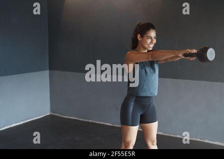 Motivation, Stärken und Sportkonzept. Bestimmt starke attraktive hispanische schwitzende Frau Workout allein Fitnessraum, tragen activewear, heben kettlebell während Stockfoto