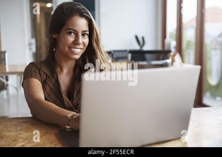 Attraktive und erfolgreiche hispanische Frau lächelt als Hände Tastatur halten, mit Laptop, Kamera glücklich aussehen, Arbeit Remote, Freiberufler schreiben neue Post Stockfoto