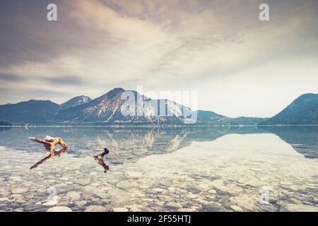 Gebrochene Äste im Wasser des stillen Sees in den europäischen Dolomitalpen. Ruhige Wasseroberfläche spiegelt den wolkigen Himmel und den Alpenhimmel wider Stockfoto