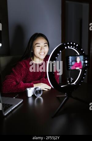 Lächelnde Frau vloggt über neue Kamera in der Dunkelkammer Stockfoto