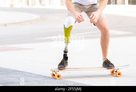 Junger Mann mit Behinderung Skateboarding auf der Straße Stockfoto