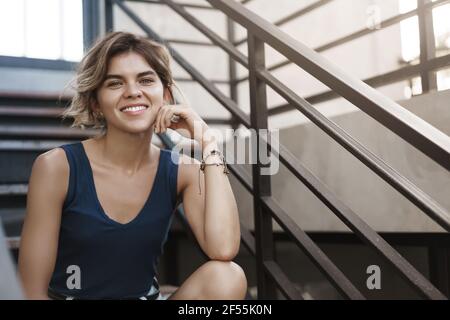 Frech gut aussehende europäische blonde junge Mädchen genießen Sommer sonnigen Tag sitzen Treppe entspannt lässig lächelnd reden Spaß haben, diskutieren jüngsten Reise Stockfoto