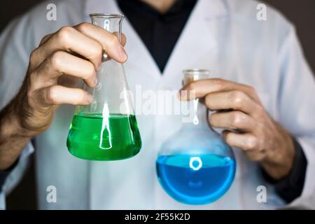 Wissenschaftler, der Kolben mit Flüssigkeiten im Labor hält Stockfoto