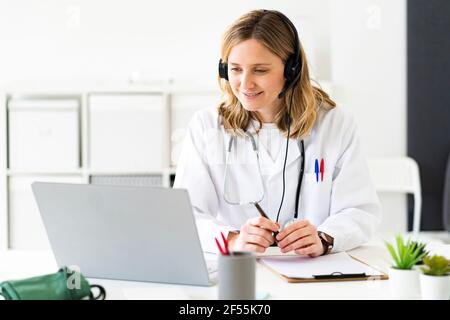 Blonde Ärztin, die Online-Beratung auf Laptop in medizinischen Klinik Stockfoto