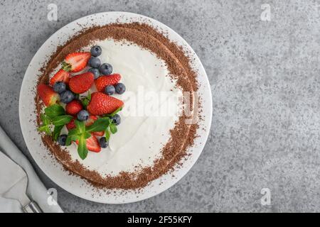 Hausgemachter Kuchen-Keks mit Mascarpone dekorierter geriebener Schokolade, frischer Erdbeere und Blaubeeren auf grauem Hintergrund. Blick von oben. Speicherplatz kopieren. Stockfoto