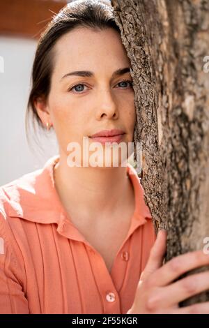 Schöne Frau umarmt Baumstamm im Garten Stockfoto