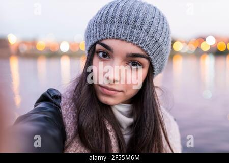 Teenager-Mädchen, das während des Sonnenuntergangs Selfie gegen den Fluss nimmt Stockfoto