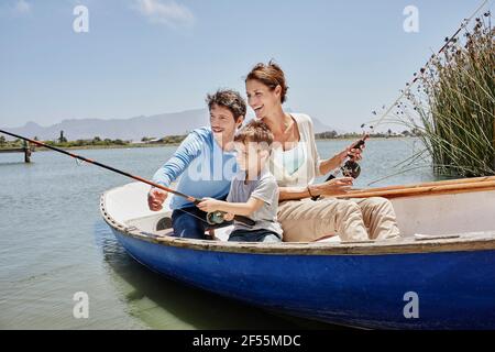 Eltern mit Angelrute sitzen bei Sohn im Ruderboot auf see Stockfoto