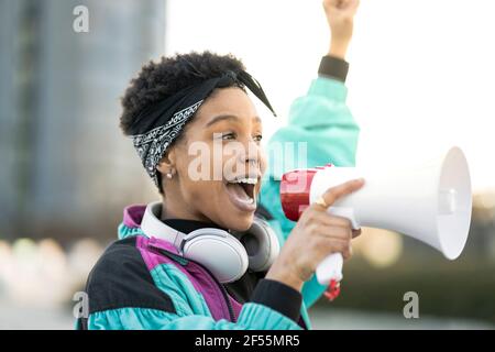 Junge Frau, die über ein Megaphon ankündigt Stockfoto