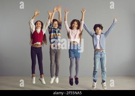 Studioaufnahme von fröhlichen energischen Kindern, die springen, lächeln und Spaß zusammen haben Stockfoto