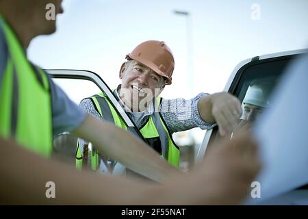 Drei Bauarbeiter im Gespräch mit dem Auto Stockfoto