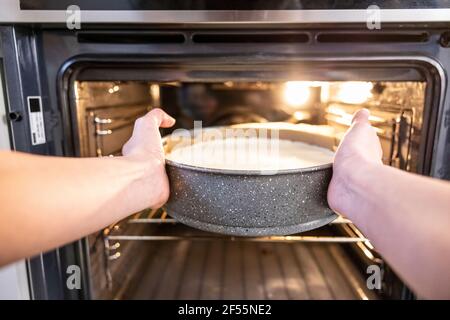 Frau, die einen Käsekuchen in den Ofen legte Stockfoto