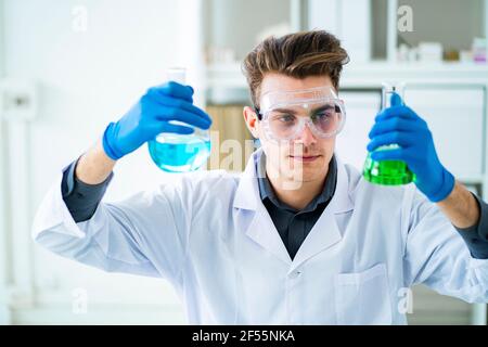 Männlicher Wissenschaftler, der chemische Kolben im Labor hält Stockfoto