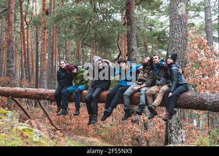 Gruppe von Wanderern, die im Herbst auf einem umgestürzten Baum sitzen Wald Stockfoto
