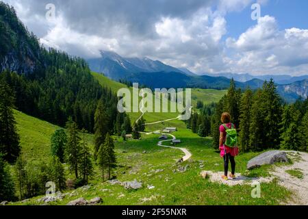 Die Wanderin steht mitten auf einem Wanderweg, der sich durch das Sommertal in den Berchtesgadener Alpen schlängelt Stockfoto