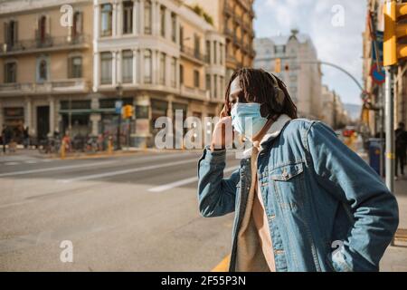 Junger Hipster mit Schutzmaske und Musik Während der COVID-19 Stockfoto